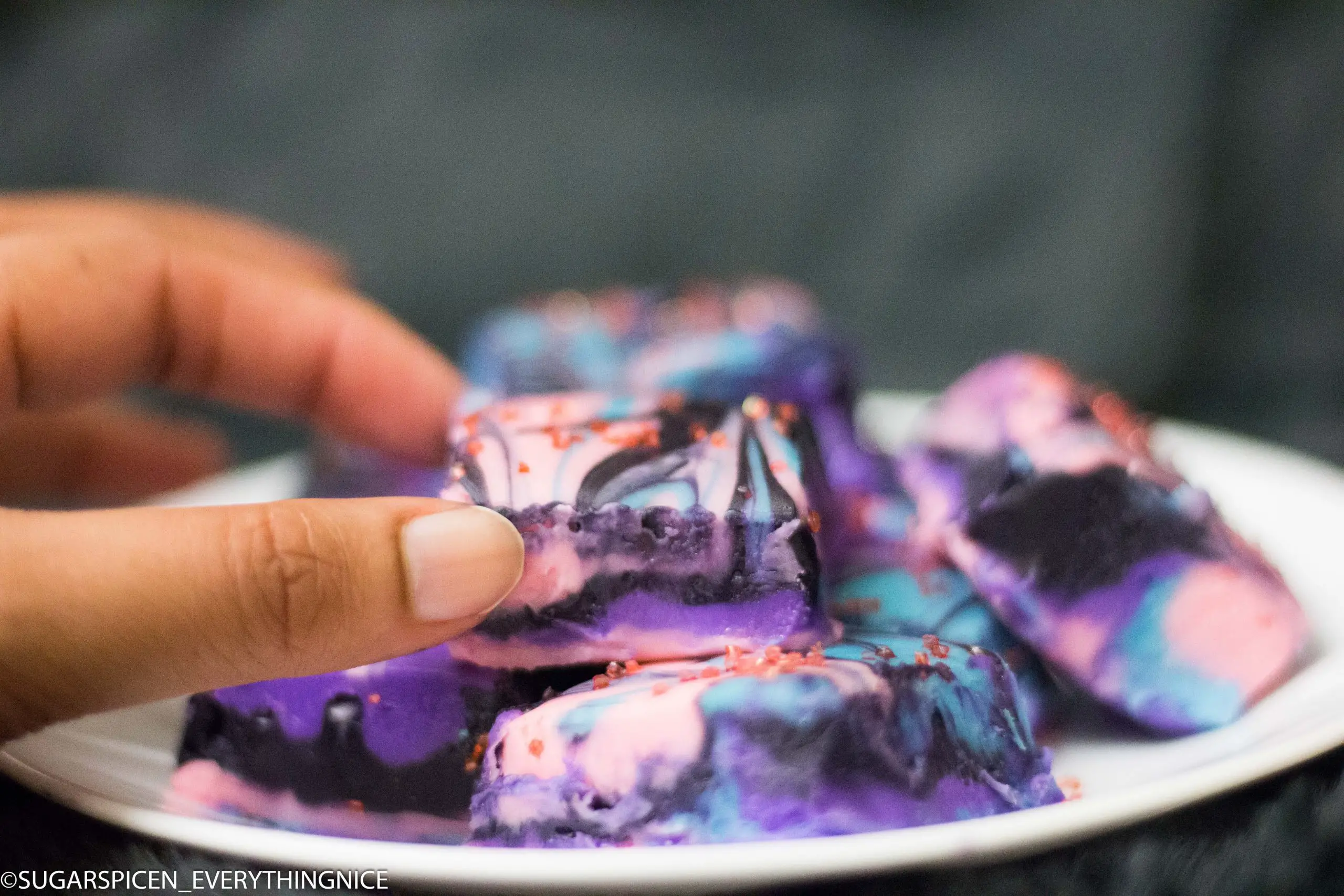 Galaxy fudges kept on a plate and a hand holding one of the fudge squares