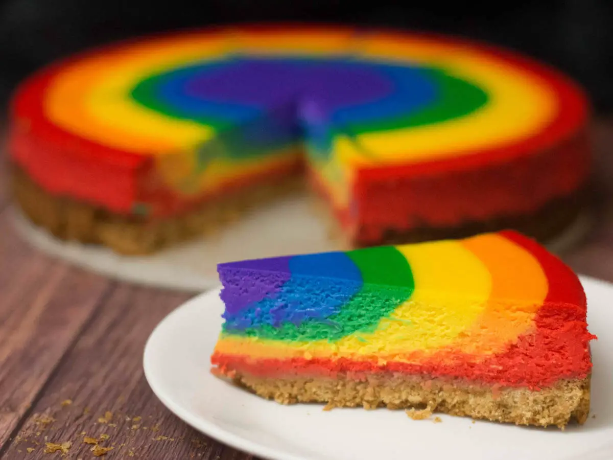 one slice of rainbow cheesecake in front of the rest of the cheesecake