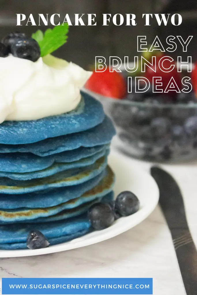 Blue pancake stack with whipped cream and blueberries. Bowl of strawberries and blueberries in the background. Pinable image of pancake for two recipe