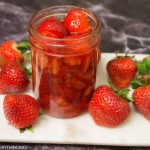 Strawberry sauce in mason jar. Starwberries lying near it