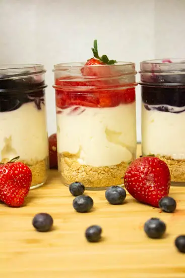 mason jars with cheesecake and topping sauce