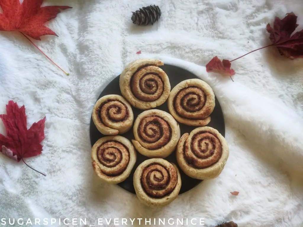 A plate of cinnamon rolls with fall leaves around
