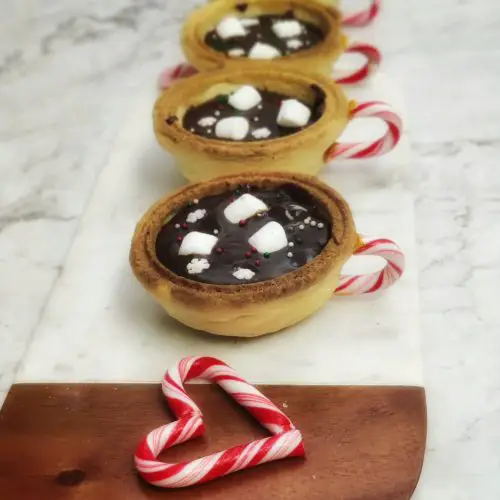 3 hot chocolate cookie cups and 1 heart made of candy cane