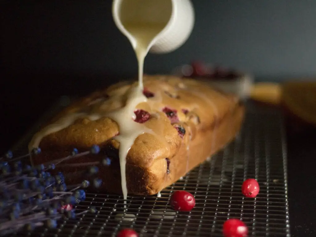 vegan cranberry orange bread drizzled with orange sugar glaze