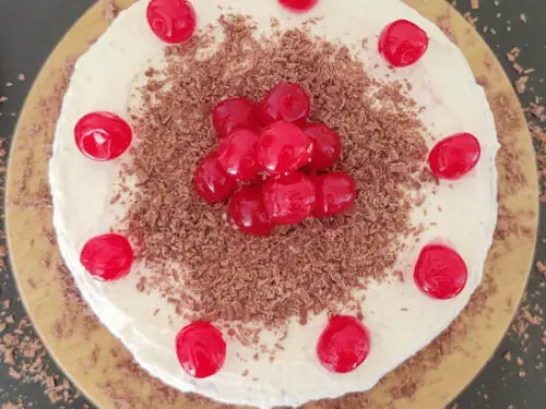 decorate the cake with cherries and chocolate shavings