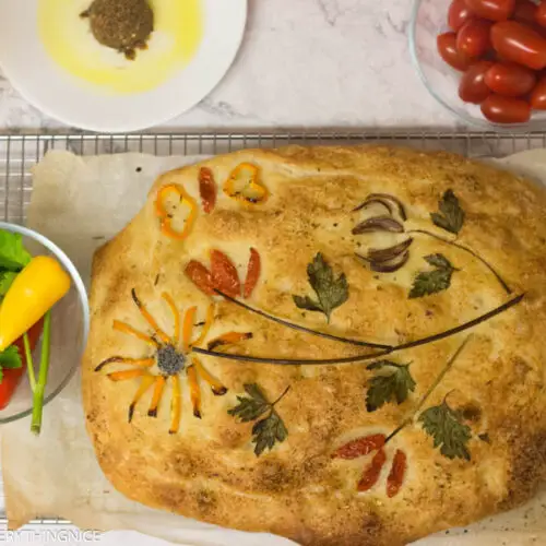 Focaccia decorated with herbs and toppings . Garden tomatoes , peppers and herbs kept on a bowl