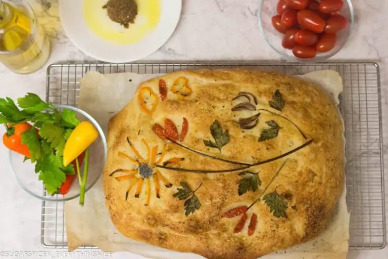Focaccia decorated with herbs and toppings . Garden tomatoes , peppers and herbs kept on a bowl