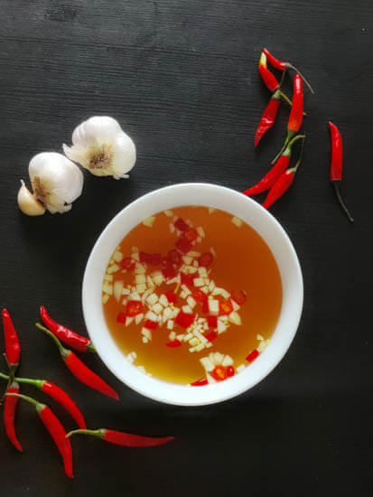 nuoc mam in a bowl with chilis and garlic around it