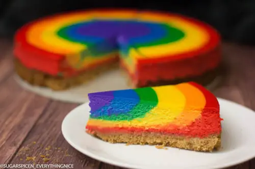 Rainbow cheesecake with a slice cut out and kept in front of it