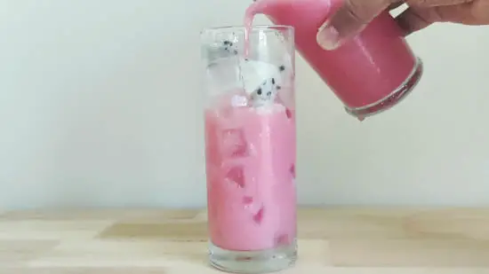pouring dragon drink to tall glass over ice cubes