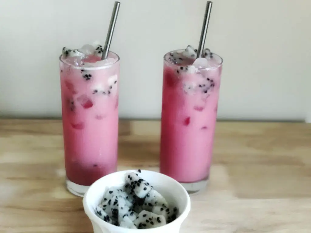 Dragon Drink in a tall glass, one kept side by side with a bowl of dragon fruits kept in front of them