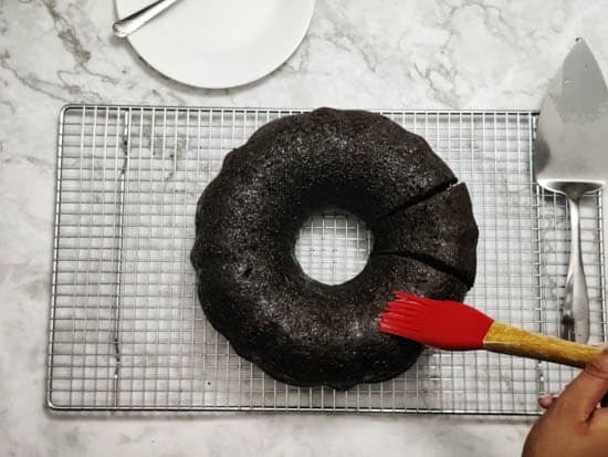 rum glaze is being brushed over chocolate rum cake