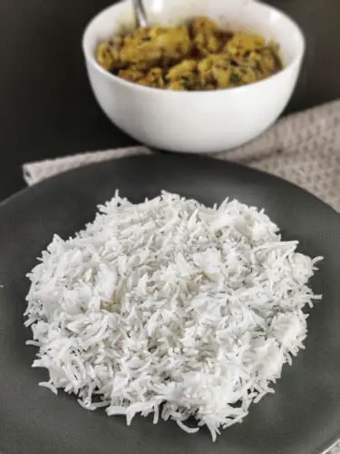 basmati rice kept on a plate with a side of chicken salan