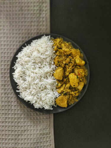 chicken salan served with rice on a black plate