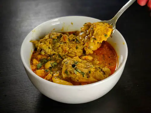 chicken salan recipe in a white bowl with a spoon