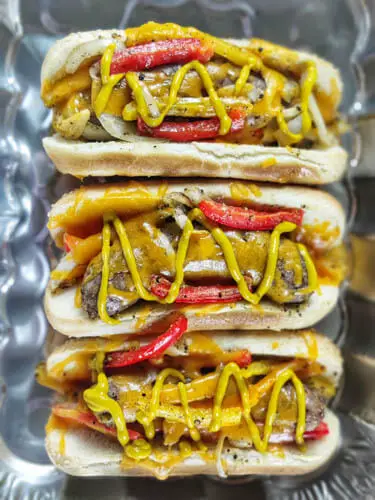 3 bratwursts in hot dog buns with mustard on top