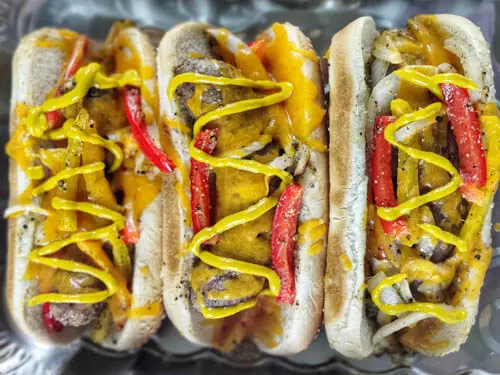 3 bratwursts in hot dog buns with mustard on top