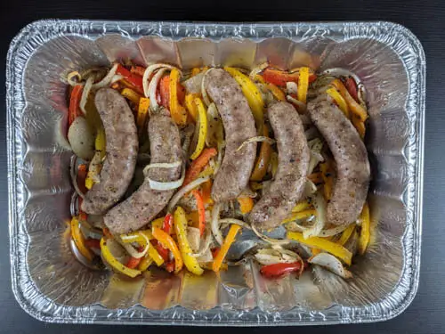 bratwurst and veggies arranged in aluminum baking pan