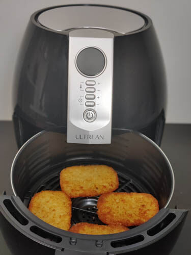 air fryer with a basket with 4 hash brown patties