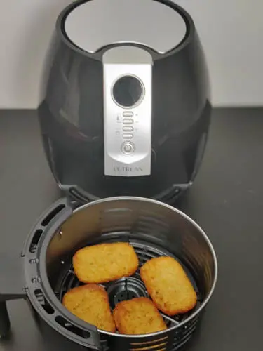 air fryer with a basket with 4 hash brown patties