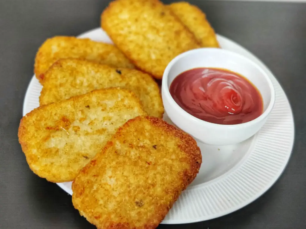 hash browns on white plate served with a side of ketchup