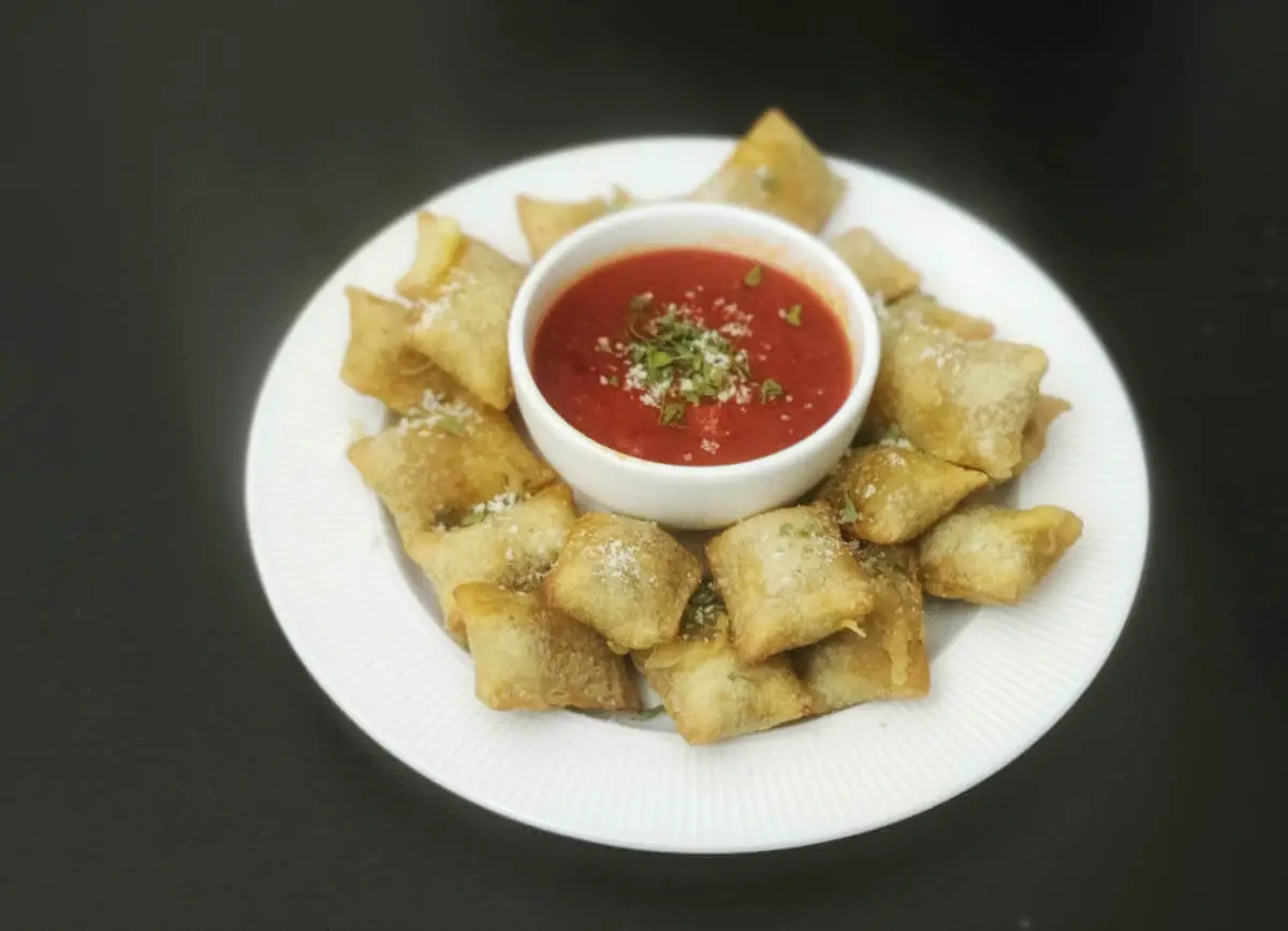 air fryer pizza rolls arranged around the marinara sauce in a small bowl