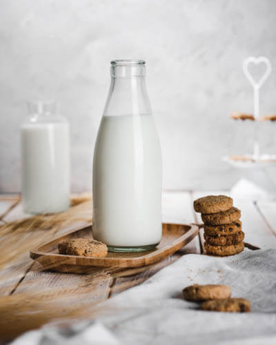 a bottle of milk with cookies kept on the side