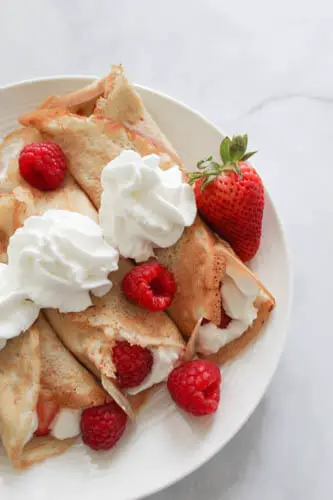 crepes with cool whip on top and raspberries and strawberries kept on top
