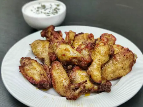 Louisiana rub wingstop chicken wings served on a white plate served with ranch on the side in a small bowl