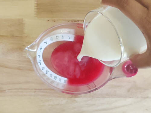 adding coconut milk to the dragonfruit, grapefruit and mango juice mix