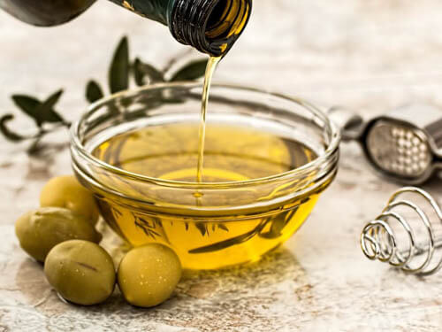 olive oil being poured into a glass bowl