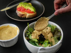 Chipotle Bitchin' Sauce (Vegan Recipe) chipotle bitchin' sauce in a container and added on salad as dressing. Toast with chipotle bitchin sauce kept in the back.