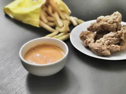 subway chipotle sauce in a small bowl surrounded by chicken wings and french fries