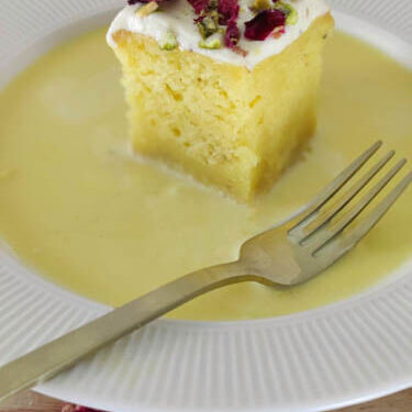 rasmalai cake slice on white plate with a fork on the side