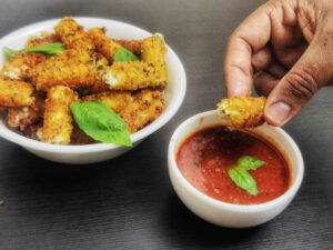 Stuffed Ziti Fritta (Olive Garden Copycat Recipe) stuffed zitti fritta in a white bowl and one dipped in marinara sauce