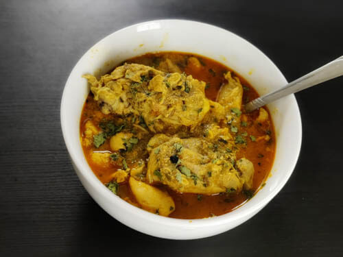 chicken salan recipe in a white bowl with a spoon