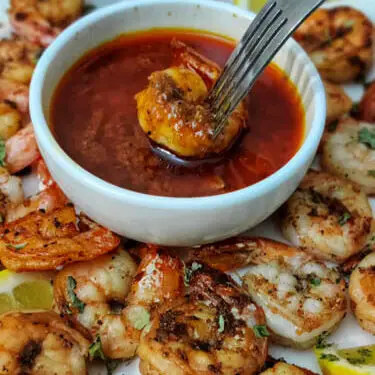 pan fried shrimp being dipped in blove sauce