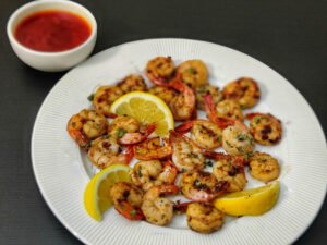 Crispy Pan Fried Shrimp (Easy Recipe) pan fried shrimp on white plate with a side of blove sauce in a white bowl